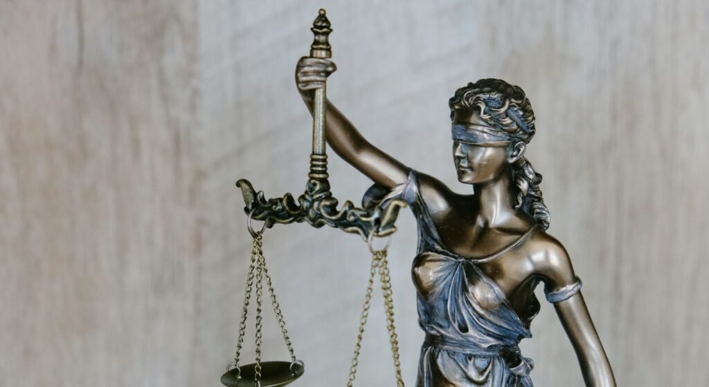 Estátua de bronze da Dama da Justiça segurando uma balança e usando uma venda, representando a imparcialidade jurídica na gestão de condomínios.